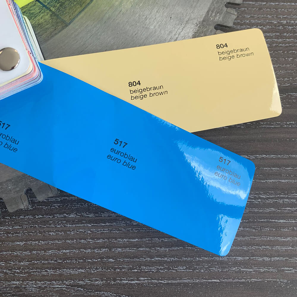 Close-up of yellow and blue vinyl swatches used for precise colour matching on fleet trailer wraps.