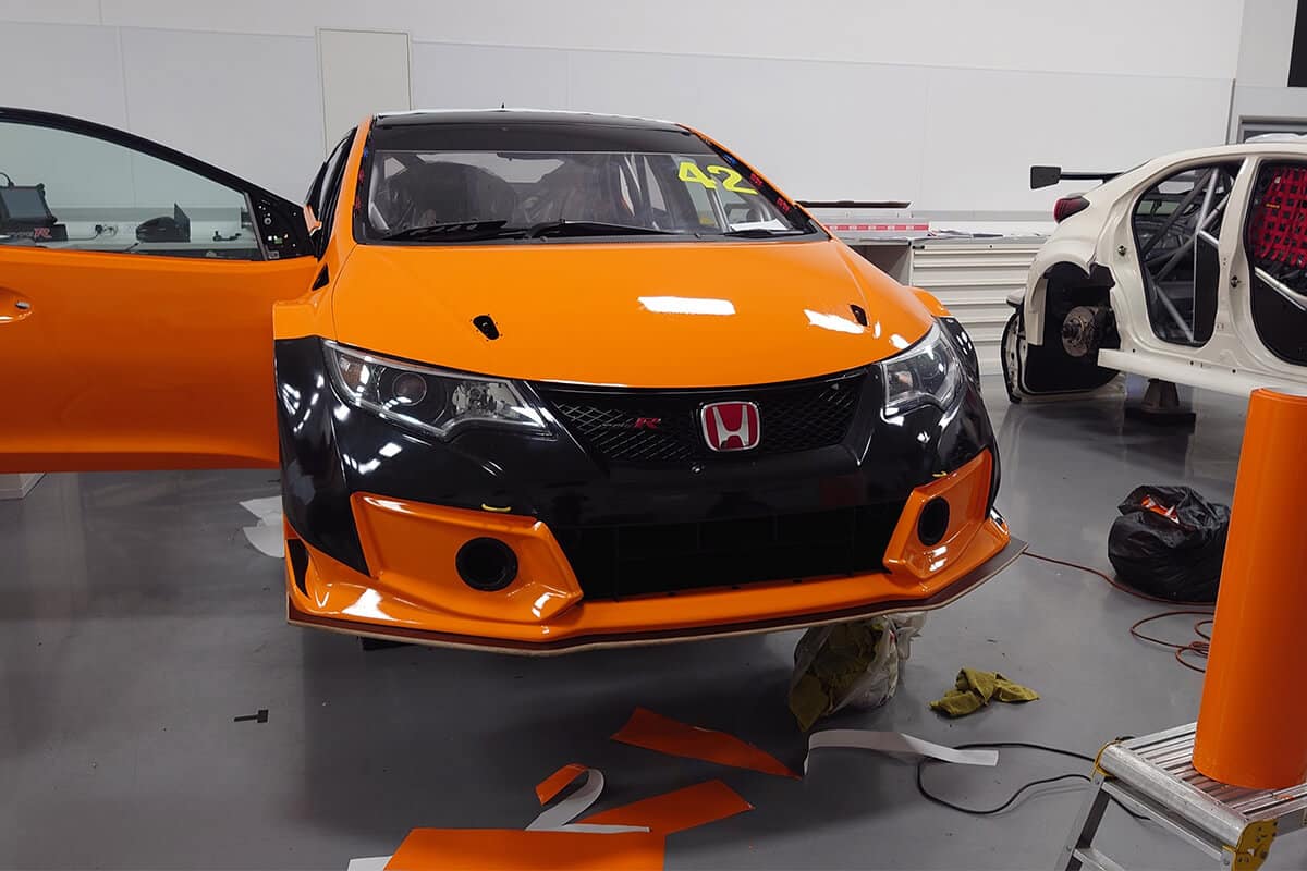 Motorsport wrap in progress – vinyl alignment on orange Honda Civic
