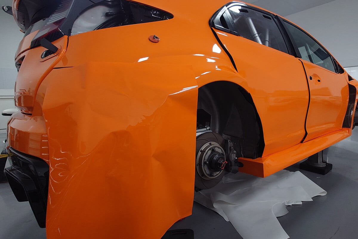 Orange and black motorsport wrap detail showing precision edges