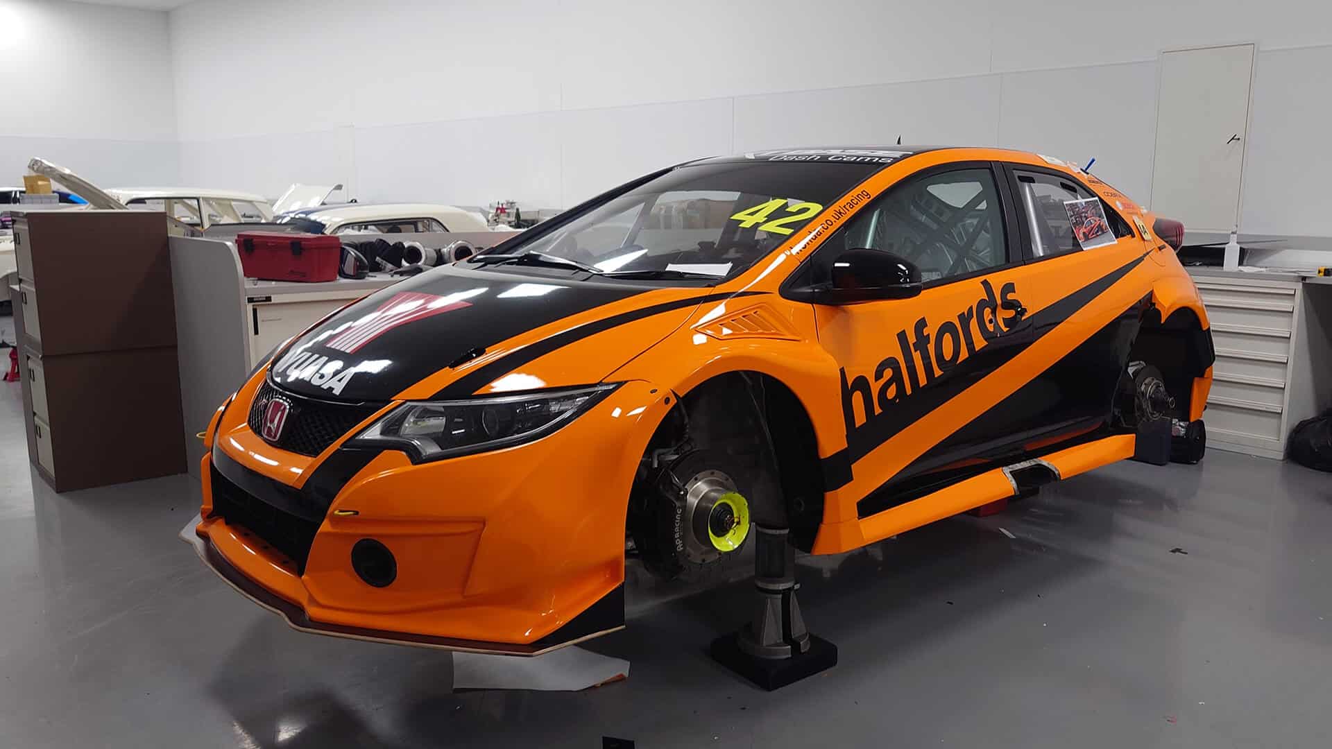 Orange race car mid-wrap installation at Korok Group’s workshop